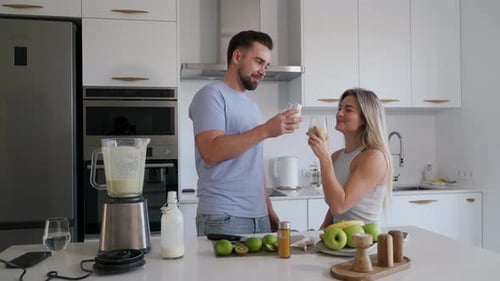 Pareja disfrutando juntos de un batido casero en una cocina moderna