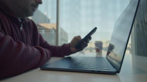Mann kauft online mit Laptop und Smartphone mit Kreditkarte im Café ein
