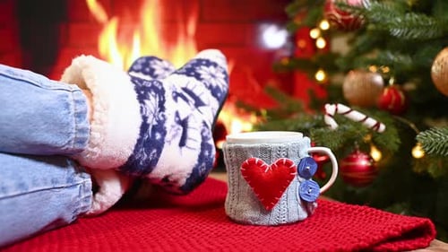 Legs in Warm Socks with a Scandinavian Ornament Against the Background of a Fireplace a Christmas