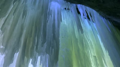 Gestreifte gelbe und blaue Eisschilde mit gezackten Eiszapfen hängen in Nahaufnahme von der Höhlendecke,