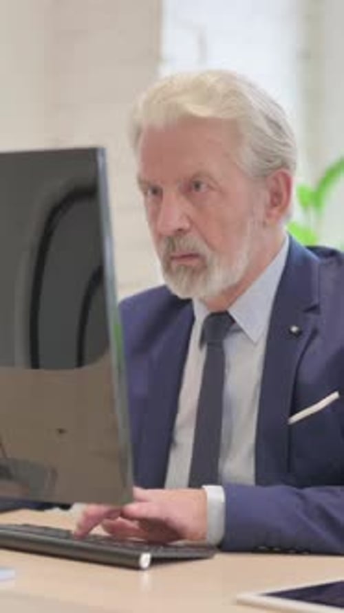 Senior Man Working Attentively at Computer in Office