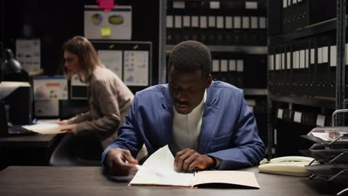 Workers Review Documents Late in Dark Office