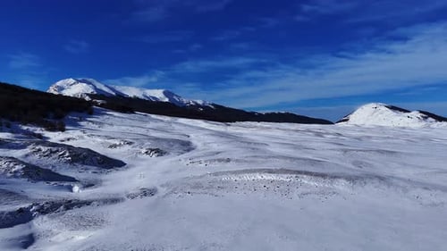 Drone Aerial Video Flying Over Snowy Plain Towards Mountains in Abruzzo Italy