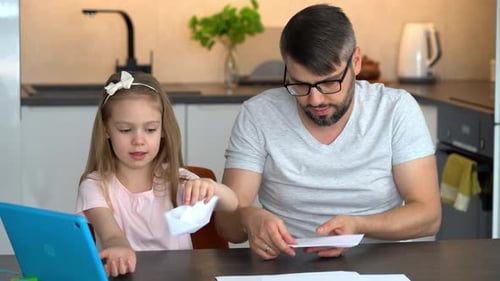 Padre e hija construyen barcos de papel en origami y utilizan un tutorial en vídeo en una tableta