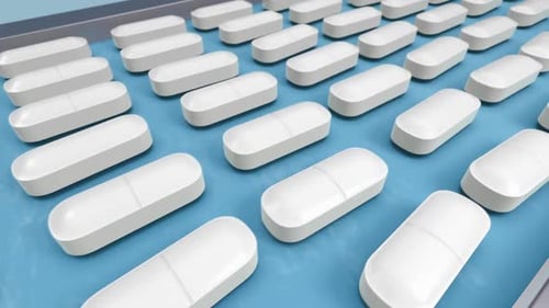 White capsules moving on blue pharmaceutical production line conveyor belt