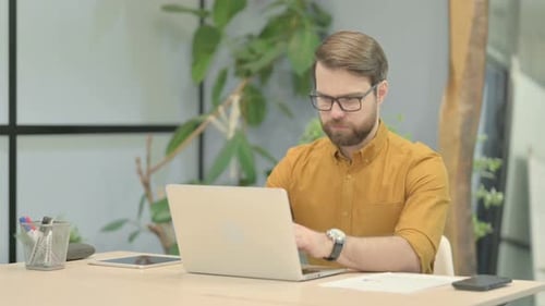 Man Typing on Laptop in Modern Workplace