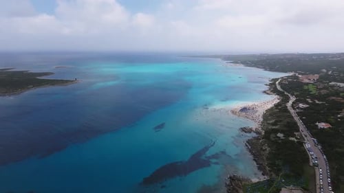 Aerial View of a Sardinian Beach with Turquoise Waters Sandy Shoreline and Beachgoers