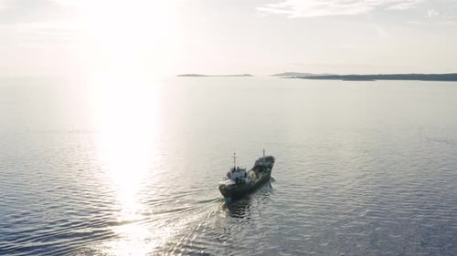 Industrial Ship Sailing Across The Adriatic Sea With Bright Sunlight Reflecting On The Surface Of Wa