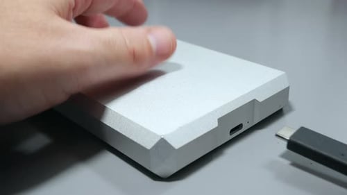 Hand connecting USB C cable into portable hard drive storage device