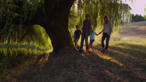 Happy family walking together in a sunny park at sunset on summer vacation