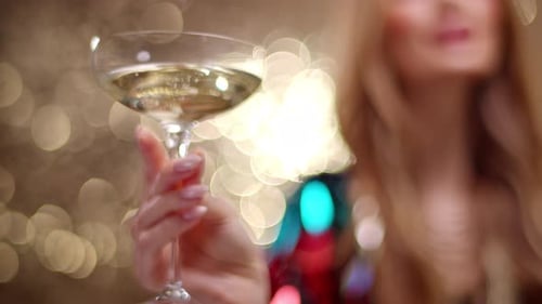 Elegant Woman Holds Champagne Glass in Festive Setting