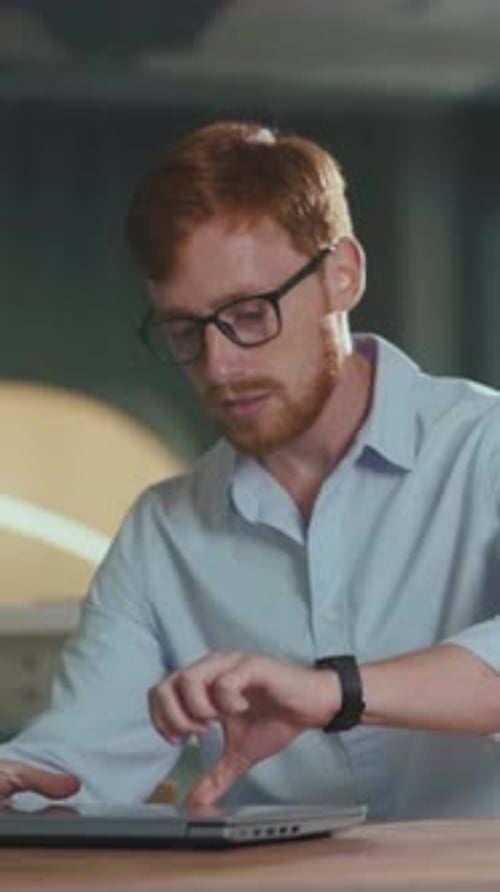 Young Man Working on Laptop in Office Environment