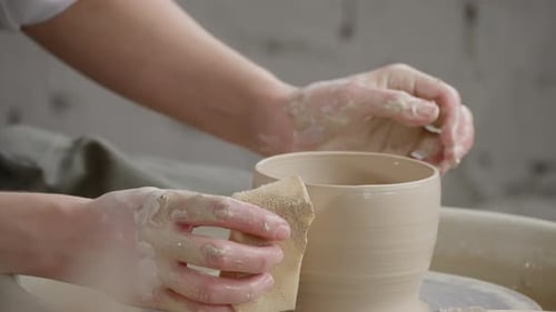 Hands shaping clay on pottery wheel in studio