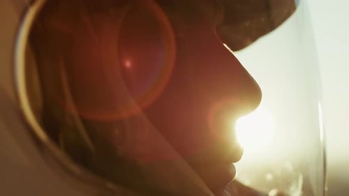 Car Driver Lowers Visor in Silhouette at Sunset After Race