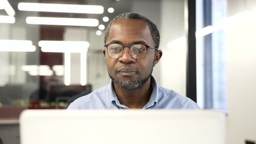 Confident african american businessman working on laptop sitting at a desk at workplace in business
