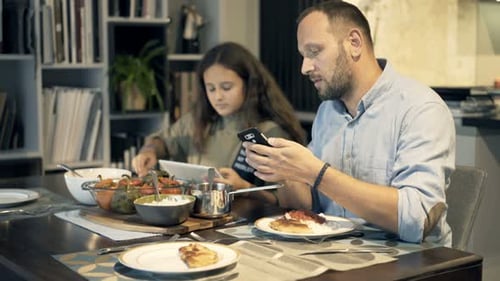 Father and daughter at dinner using technology