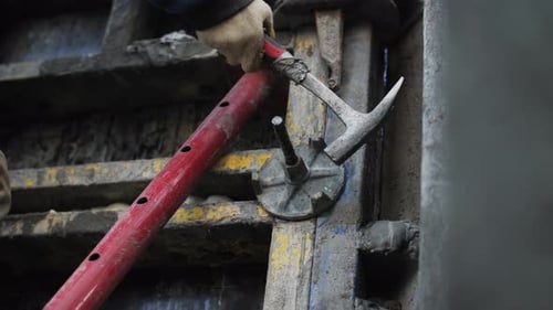 L'ouvrier ajuste la connexion au coffrage à l'aide d'un marteau
