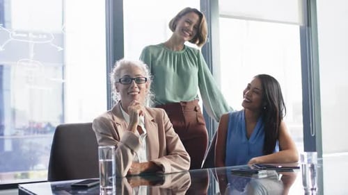 Businesswomen in meeting room, discussing project and smiling, teamwork concept