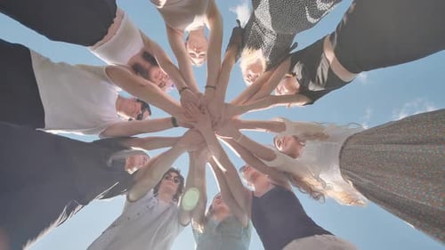 Group of Young Women is Joining Hands in a Circle Outdoors Showing Their Unity and Teamwork