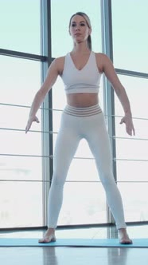 Woman Doing Squats on Blue Mat Indoors