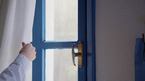 Woman Hand in White Shirt Open Curtains and Vintage Old Window Blue Color