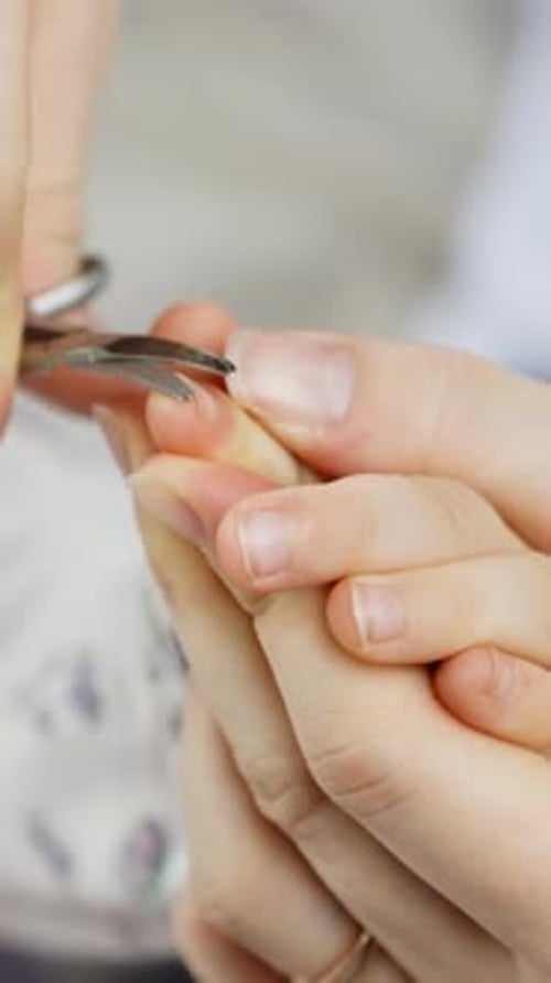Parent Trims Child's Nails with Small Scissors