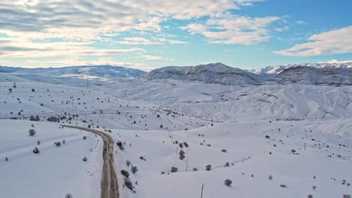 Aerial View of Snow-Covered Mountain Road in Winter Landscape