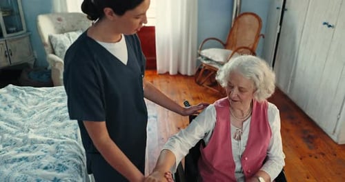 Caregiver assisting senior woman in wheelchair indoors