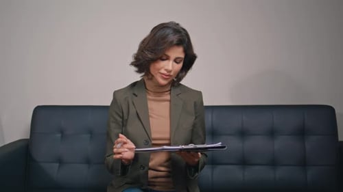 Business Woman Signing Documents on Clipboard in Modern Office Closeup