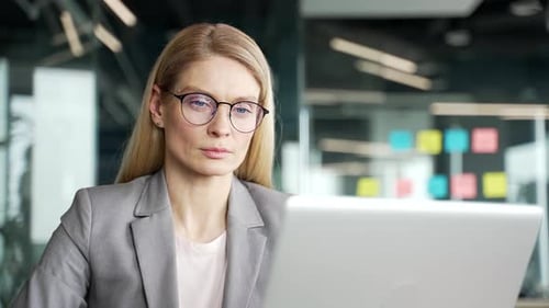 Businesswoman Concentrates While Using Laptop in Office