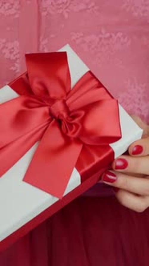 Person Holding Beautifully Wrapped Gift with Red Ribbon