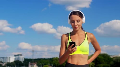 Woman in sportswear listening to music on headphones