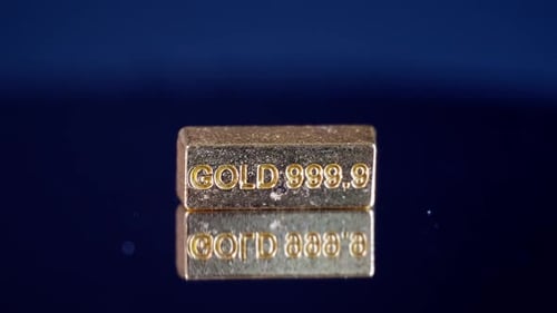 Closeup of 999,9 Gold Bar Spinning on Reflective Surface
