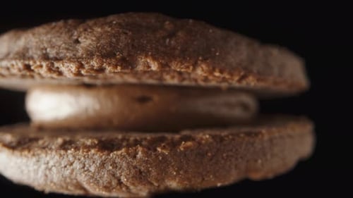round cookies with chocolate cream between the two halves. extreme close-up, the camera pulls back.