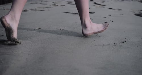 Close-up of feet running on the beach in sand
