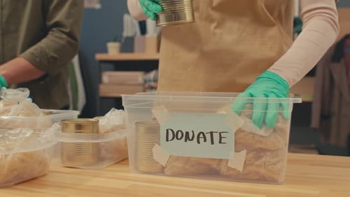 Les coordinateurs d'un projet caritatif ajoutent de la nourriture à la boîte de dons