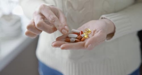 Pharmacy and Treatment Concept Close Up View of Caucasian Woman Holding Capsules and Tablets in Her
