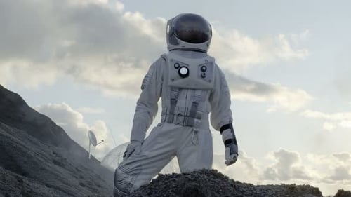 Astronaut Looking Around while Standing on the Hill of the Frozen Alien Planet. In the Background H