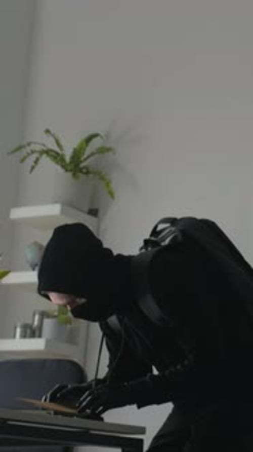 Vertical of Masked Man Breaking into Office Stealing Folder with Secret Data