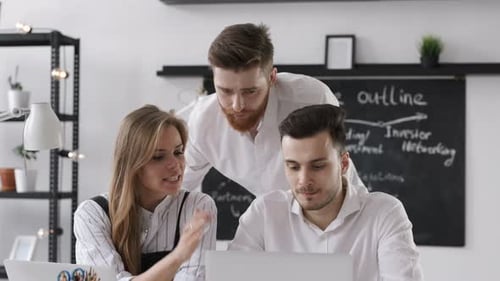 Young entrepreneur sharing startup finance success on computer in bright loft office
