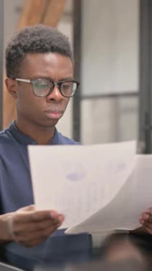 Young African Man Reading Documents in Office