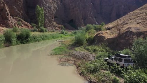 Aerial View Of Offroad Vehicle Driving In Green Area By Creek