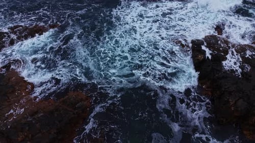Waves crash against rocky shoreline at the ocean during daytime