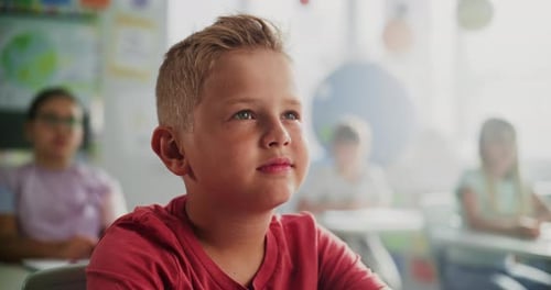 Primary School Pupil Sitting at Desk Raising Hand to Give Correct Answer