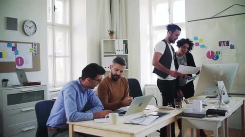 Young business team collaborating on laptop in modern open office space