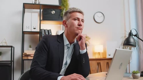Handsome Young Businessman Thinking Business Ideas While Sitting with Laptop at Home Office Desk
