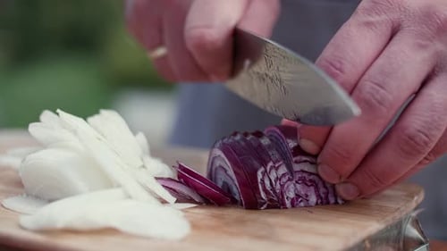 Hands Cutting Red Onion on Wood Board