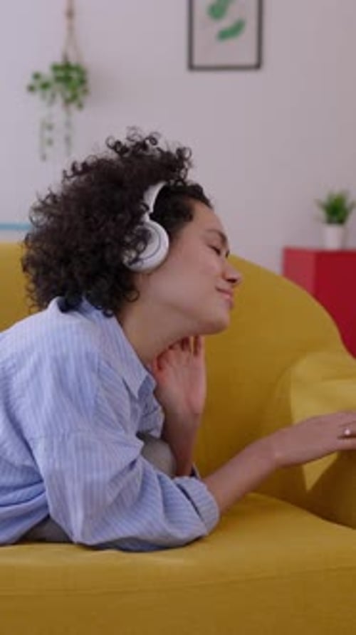 Woman Listens to Music on Couch with Headphones