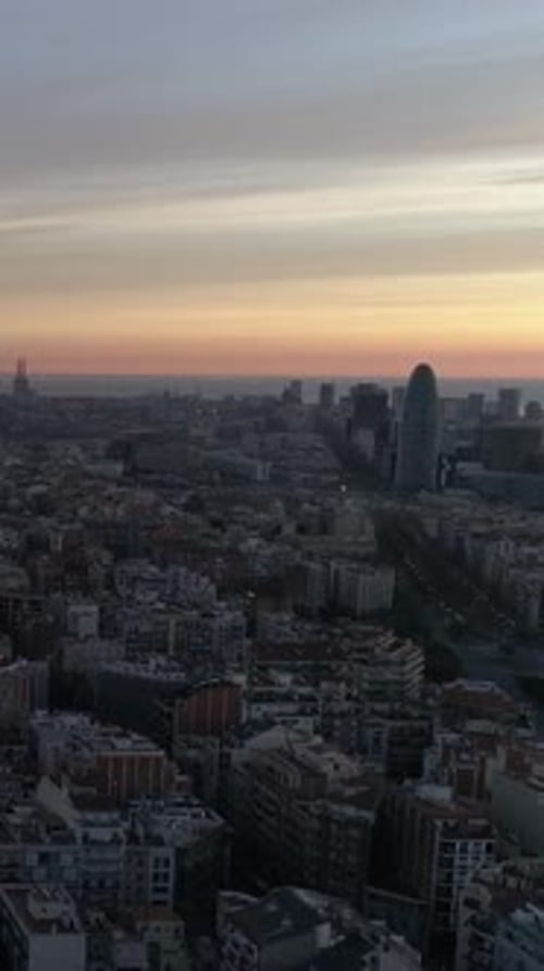 Vertical Video of Barcelona city at sunset with orange sun Aerial