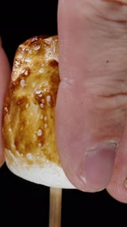 Fingers Squishing a Toasted Marshmallow on a Stick